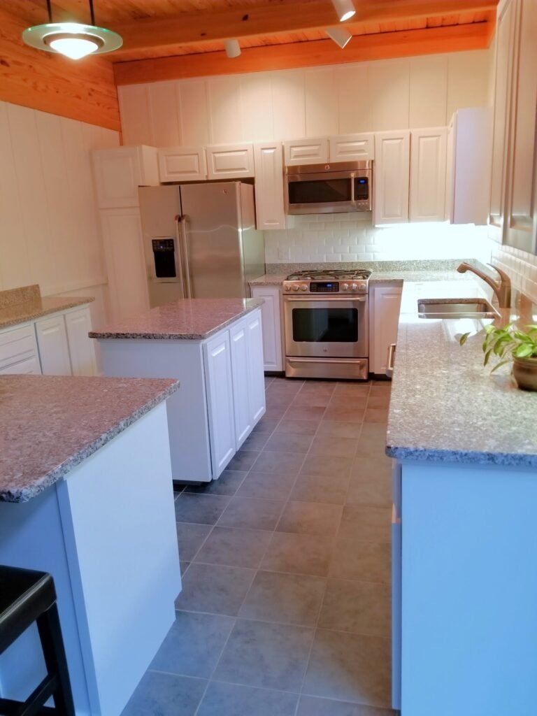 After shot of white cabinets restored showing full kitchen with islands and overhanging cabinets