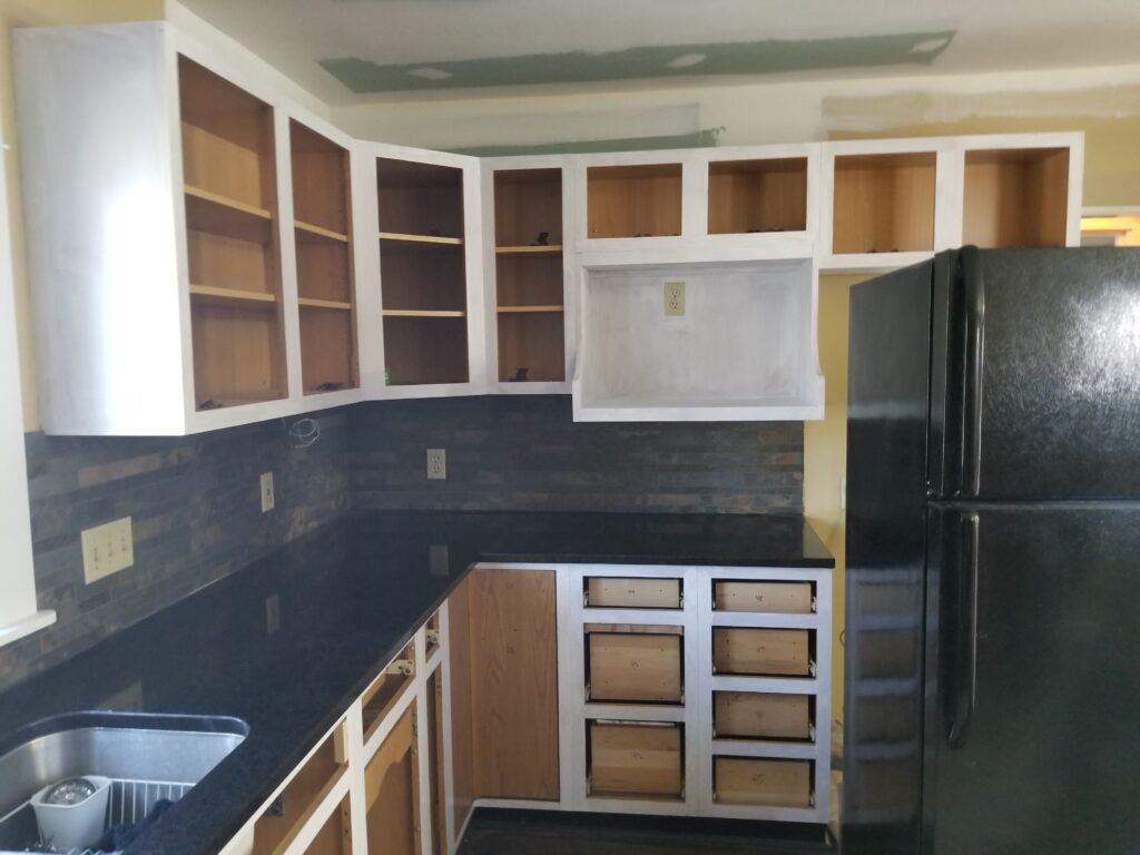 A kitchen with cabinet doors removed is shown to demonstrate the work in progress state of a renovation