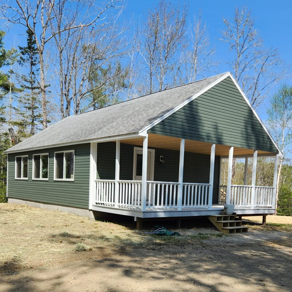 Single story green house with a white trim porch