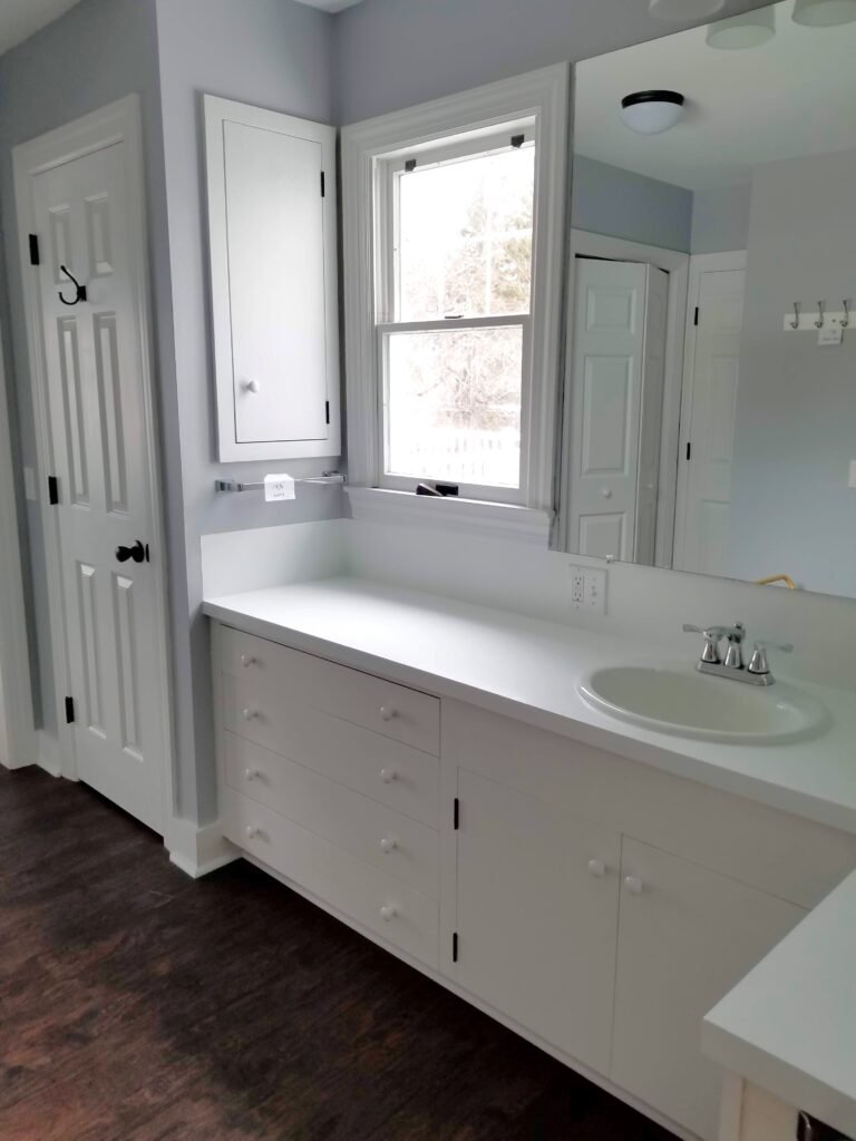 A newly renovated bathroom sink and counter are pristine white with soft blue walls