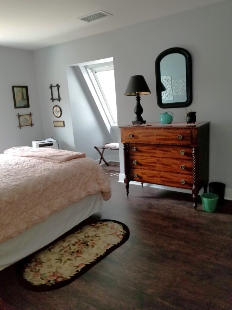 A loftlike bedroom has a skylight and gentle hues of blue to the walls and a large pink bed in the center of the room