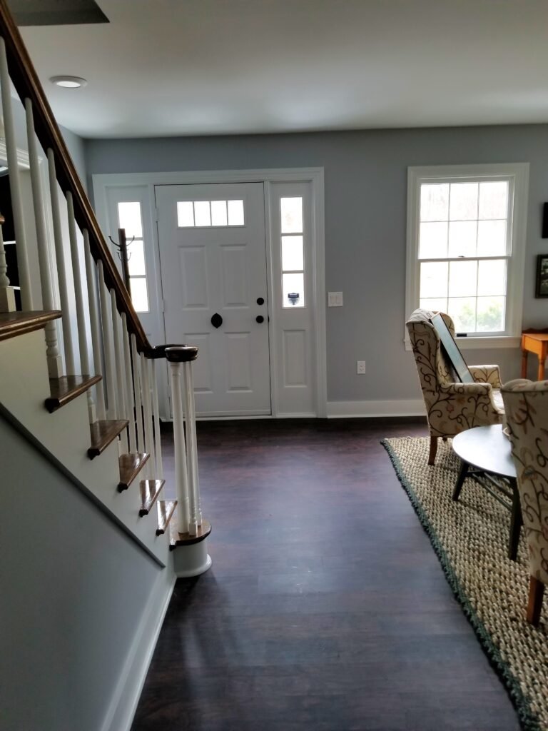 A foyer or entryway where the stairs face the front door and match the color of the wall, which are both a cool grey and add a modern look