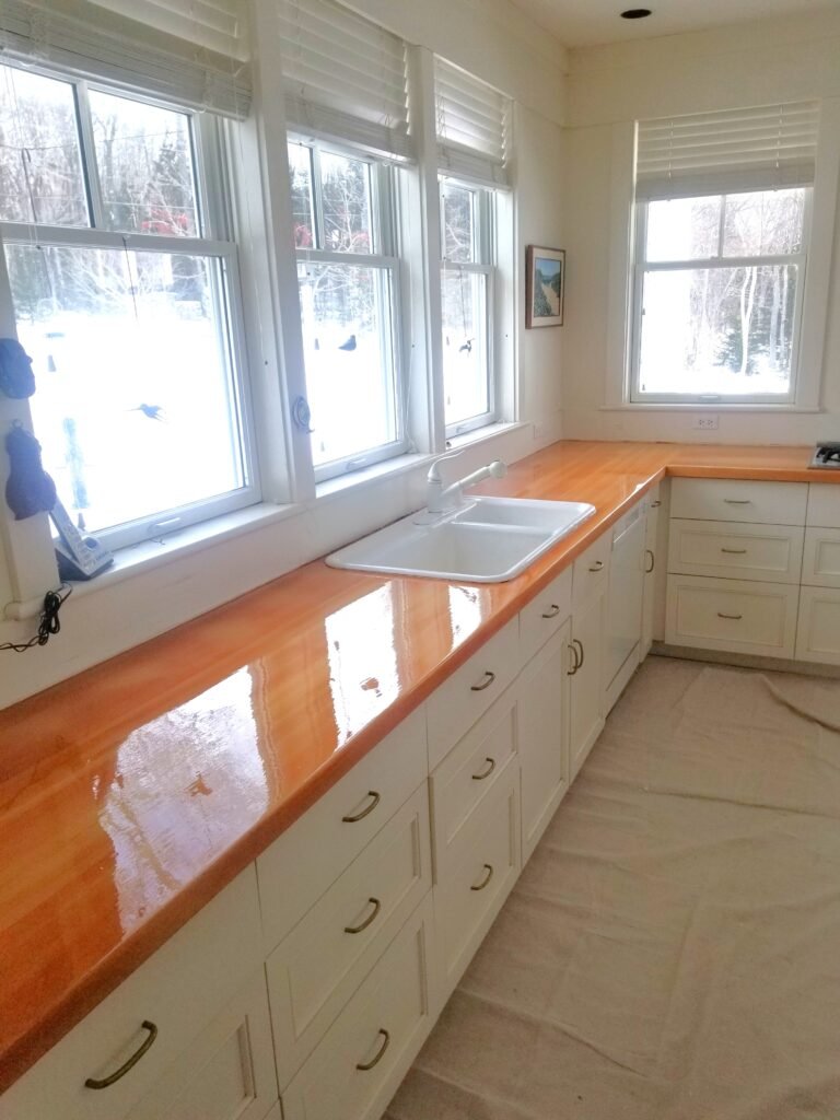 Freshly varnished wooden countertops compliment newly painted white cabinets and walls